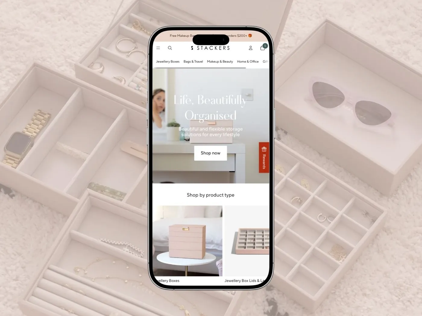 Stackers Australia Shopify store on a phone, jewellery boxes in the background